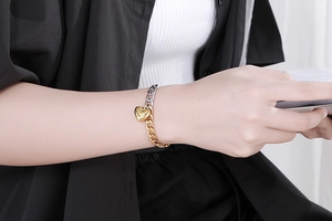 Close-up of gold and silver mixed metal chain bracelet with a heart pendant on wrist