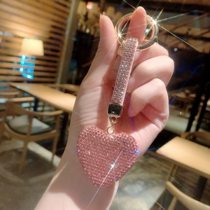 Close-up of heart keychain with pink rhinestones and a gold metal ring on a leather strap