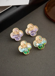 Macro shot of gold floral earrings with pastel enamel gradient and small white pearls