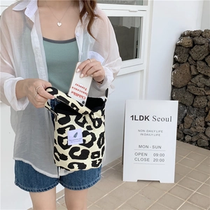 Detail of leopard print canvas tote bag featuring stylish blue fabric label and top handle