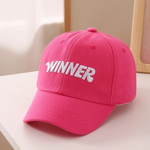 Close-up of pink baseball cap featuring white WINNER embroidery and premium cotton stitching