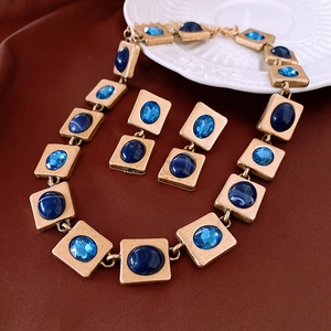 Close-up of vintage gold necklace and earrings set with marbled blue gemstones