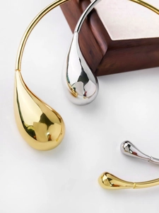 Polished gold and silver metal collars with water drop pendants on wooden box