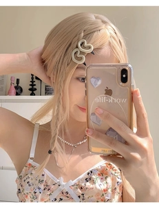 Détail de deux pinces à cheveux coeur beige mat sur une coiffure tressée blonde