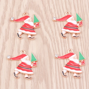 Gold Santa Claus charms with green tree and rhinestone on wooden background