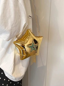 Detail of star-shaped crossbody bag with green rhinestones and gold fringe tassels