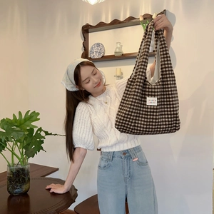 Close-up of brown checkered plaid tote bag with small fabric label and thick woven texture