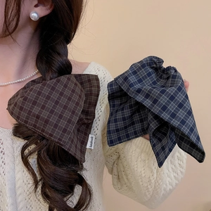 Detail of handmade plaid bow hair tie showing checkered fabric texture on braided hair