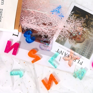 Close-up of colorful resin alphabet charms with glitter and gold foil on white mesh