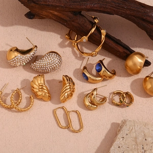 Collection of retro gold earrings with zircon and blue gemstones on stone background