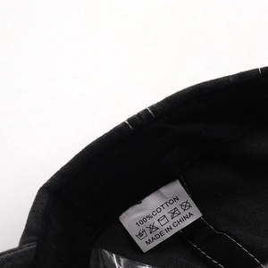 Detailed close-up of 100% cotton wash care label on a black baseball cap