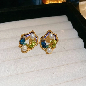 Detailed shot of vintage gold-plated pearl earrings with blue gems in a jewelry box