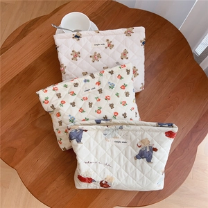 Three quilted cotton cosmetic bags with cute bear prints on a wooden table setup