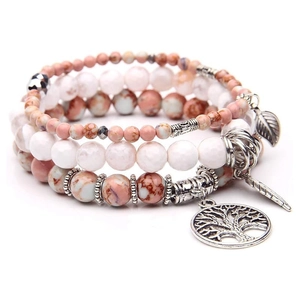 Close-up of bohemian beaded bracelet set with tree of life and feather charms