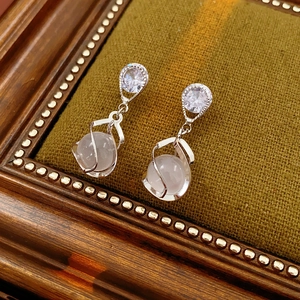 Close-up of elegant silver drop earrings with faceted crystal and white cat eye stone