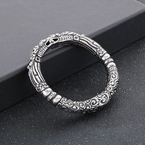 Macro detail of vintage dragon and cloud relief carvings on a retro silver cuff bracelet