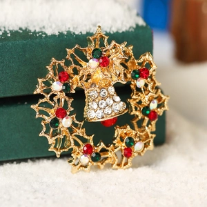 Christmas wreath brooch with bells and colorful rhinestones on a green gift box