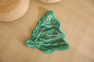 Detail of green Christmas tree plush pillow shell with festive embroidery on wood floor