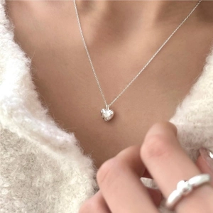 Close-up of 925 sterling silver heart pendant necklace on a cozy white knit sweater
