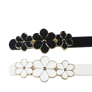 Pair of black and white flower hair clips with gold metal edges and enamel finish