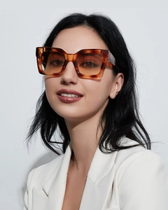 Close-up of tortoise shell square sunglasses with orange gradient lenses on a model