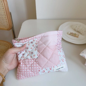Detail of pink floral quilted pouch with simple wish label and silver metal zipper