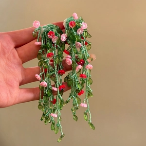 Detailed view of green beaded floral tassel earrings with handmade pink flowers
