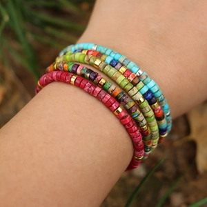 Detailed view of bohemian multi-layered heishi bead bracelets with gold spacer accents