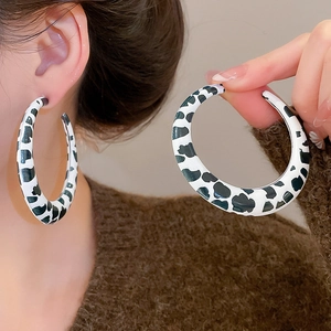 Close-up of oversized hoop earrings with black and white cow print and silver needles