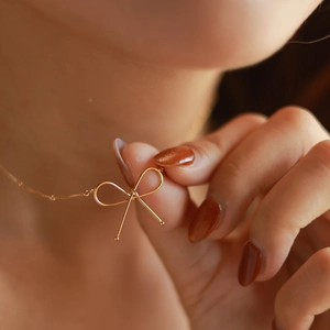 Gold bow necklace in 18k titanium steel shown on neck with elegant minimalist design