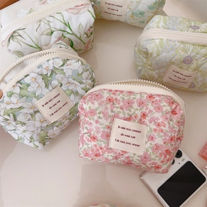 Assorted floral quilted cotton pouches with zipper closure and phone for size reference