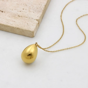 Elegant gold teardrop pendant necklace set with minimalist link chain on stone decor