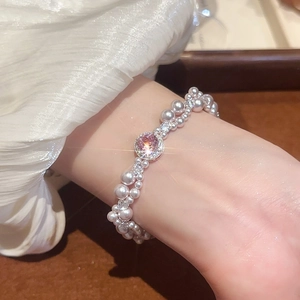 Detailed close-up of a pink gemstone and double-row pearl beaded bracelet on a wrist