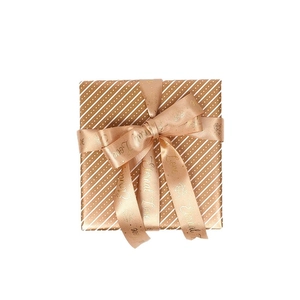 Golden foil striped gift wrapping paper roll with elegant champagne satin ribbon bow