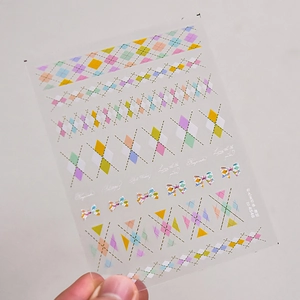 Detail showing colorful diamond plaid nail art stickers with bow motifs and artistic phrases
