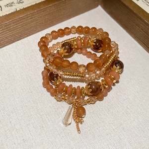 Close-up of four-piece beaded bracelet set featuring warm orange crystals and gold accents