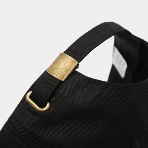 Detail of adjustable brass buckle and black twill cotton texture on the baseball cap
