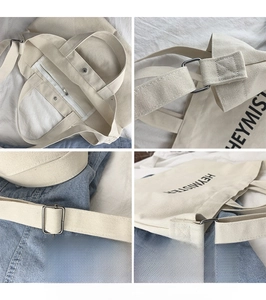 Detail view of adjustable metal buckle and zipper closure on the beige canvas bag