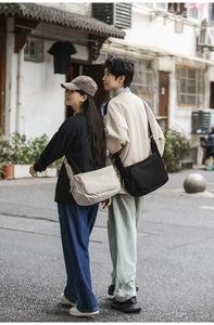 Outdoor shot showing black and cream waterproof nylon messenger bags worn by models