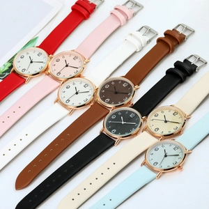 Flat lay of minimalist slim quartz watches with colorful leather straps on white background