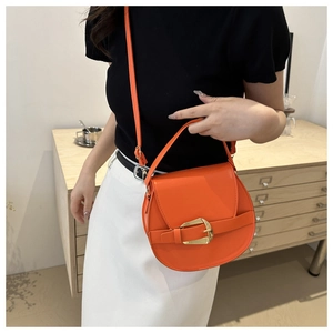 Detail of elegant orange saddle bag with gold buckle and adjustable shoulder strap