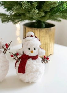 Close-up of plush Christmas snowman ornament with red knit scarf and twig arms