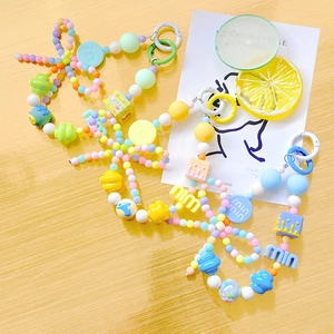 Colorful beaded phone charm with alphabet and cartoon beads on a wooden background