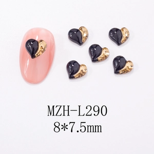 Macro view of heart-shaped black and gold nail charms showing 8x7.5mm size on pink nail tip
