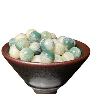 Engraved Bodhi root beads with Sanskrit mantras in a ceramic bowl for jewelry DIY