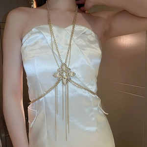 Detail of gold body chain featuring a pearl cross pendant and shimmering tassels