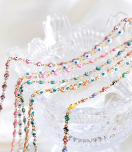 Detailed close-up of colorful evil eye beads on a golden chain over a glass bowl