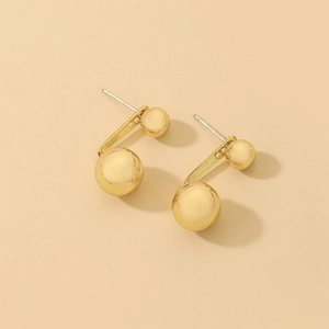 Macro view of gold-plated metal spherical stud earrings with polished double ball design