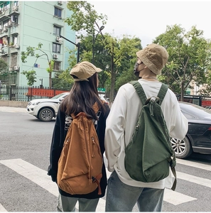 Street view of retro canvas backpacks in brown and dark green colors on models