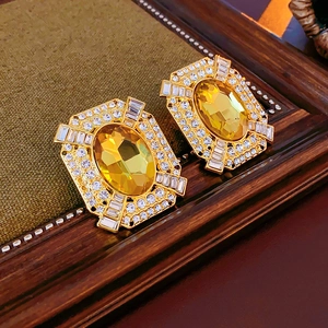 Dettaglio di orecchini d'oro con pietre ovali gialle e piccoli diamanti bianchi brillanti